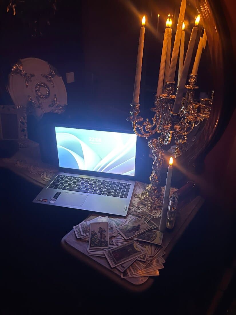 Mesa de leitura à luz de velas, com castiçal dourado e o baralho espalhado